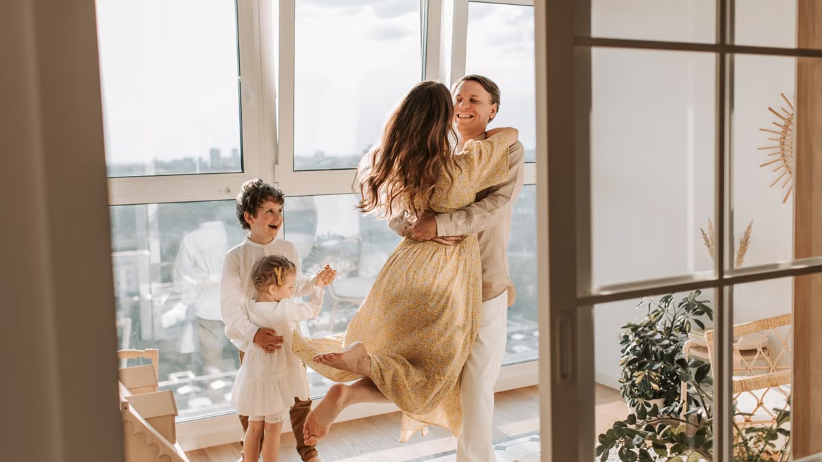 A joyful family embraces in a sunlit modern apartment, celebrating togetherness and love.